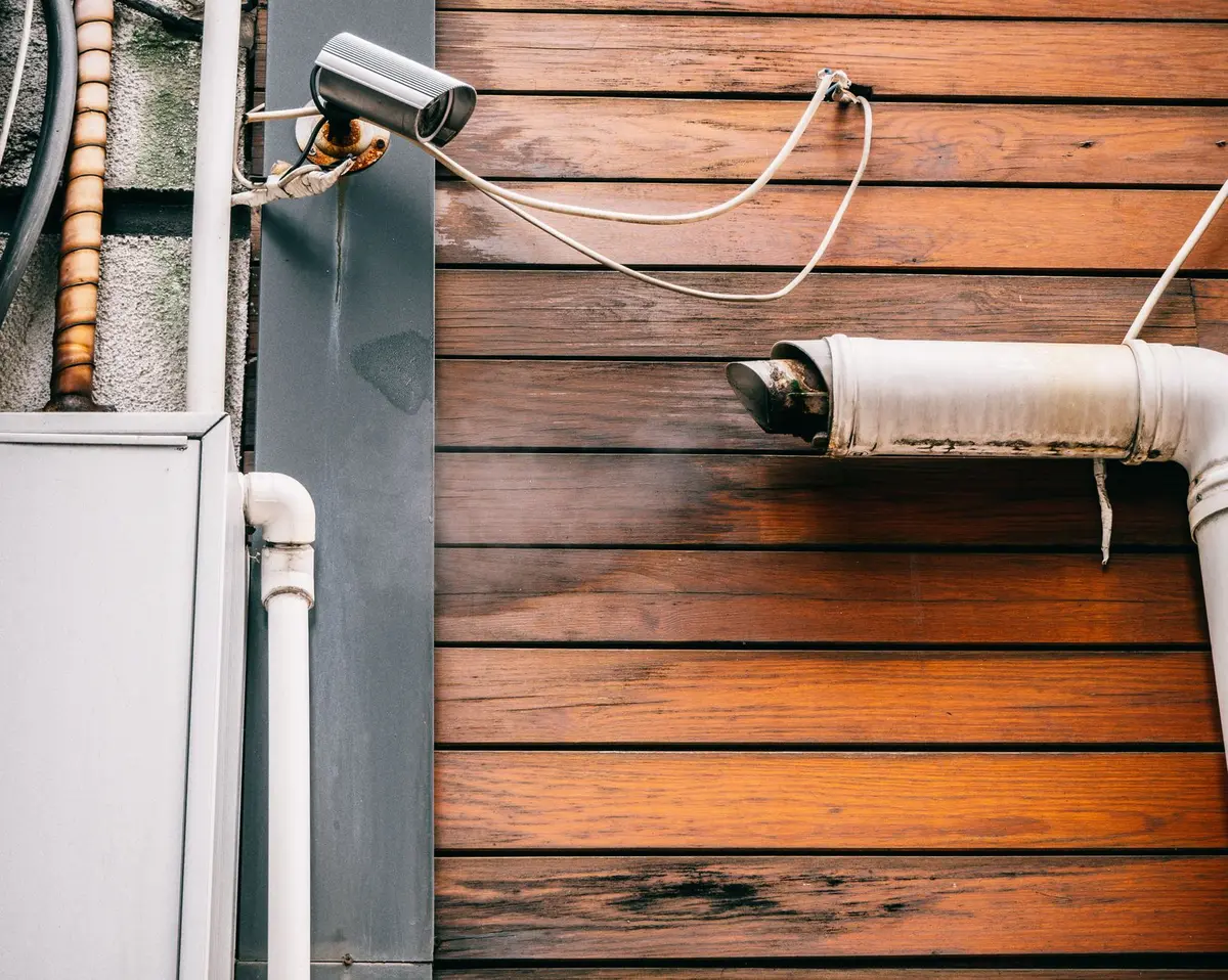 Main d'une personne en gants scellant une fissure sous une porte avec du matériel étanche