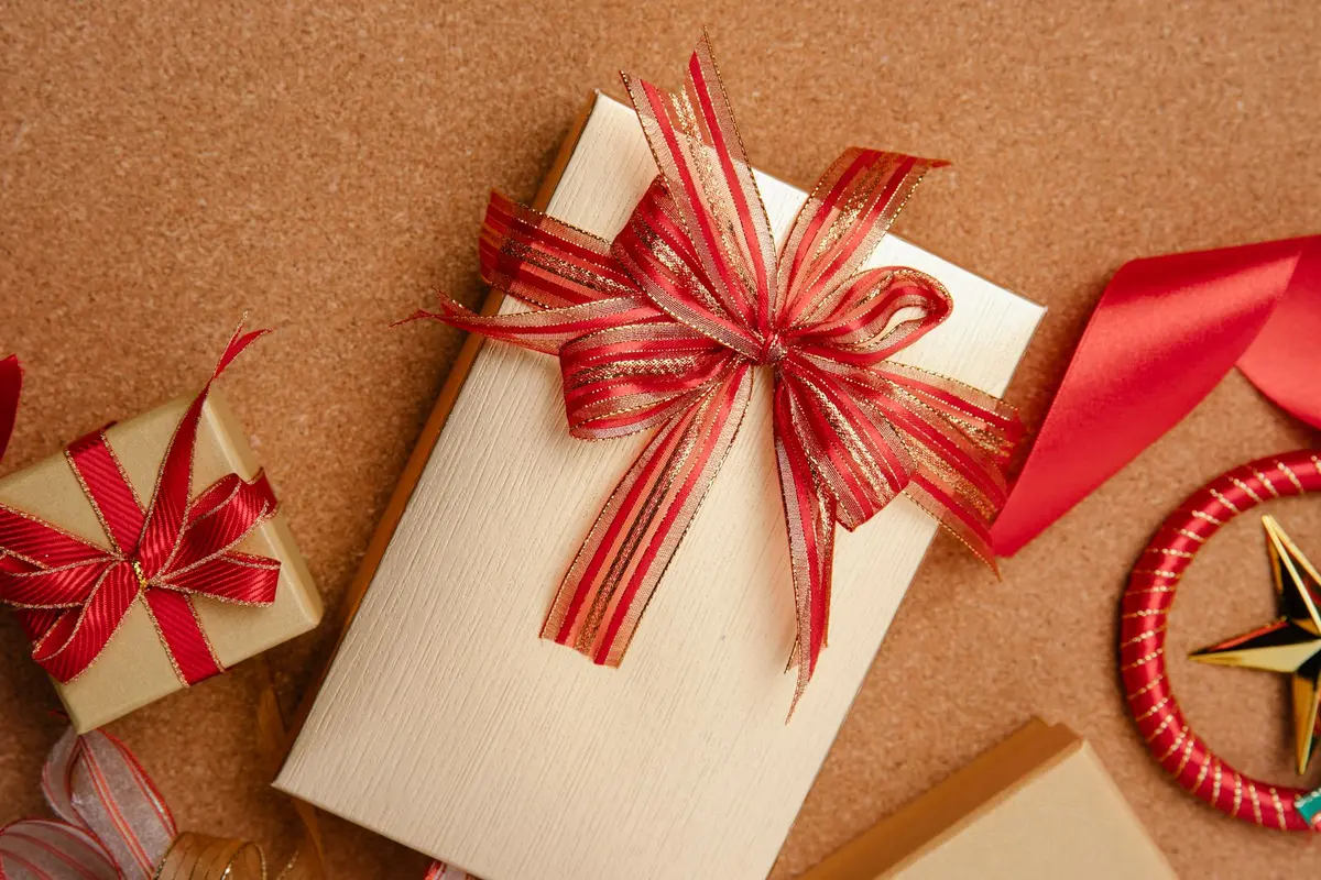 Paquet cadeau emballé avec ruban rouge sur fond neutre avec dates de décembre