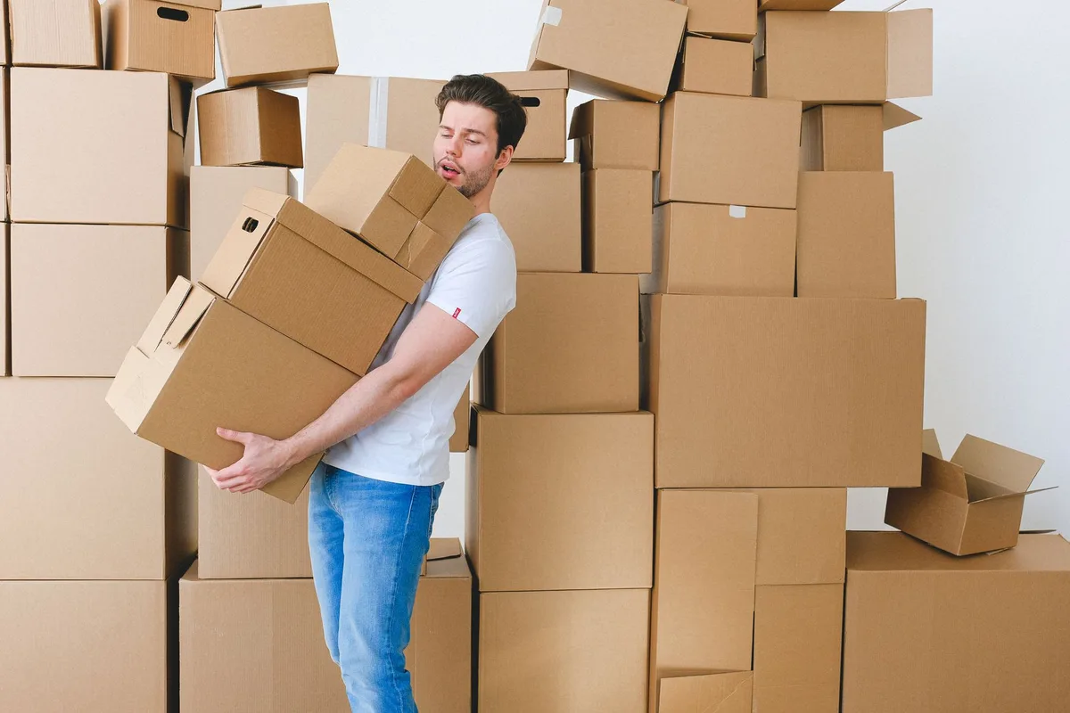 Garage encombré avec cartons empilés, outils et traces de rongeurs sur le sol