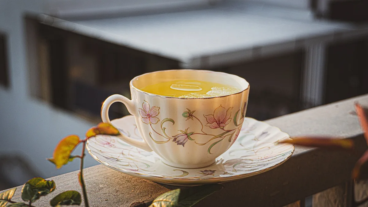 Table de balcon au coucher du soleil avec carnet, tasse et silhouette d'une main