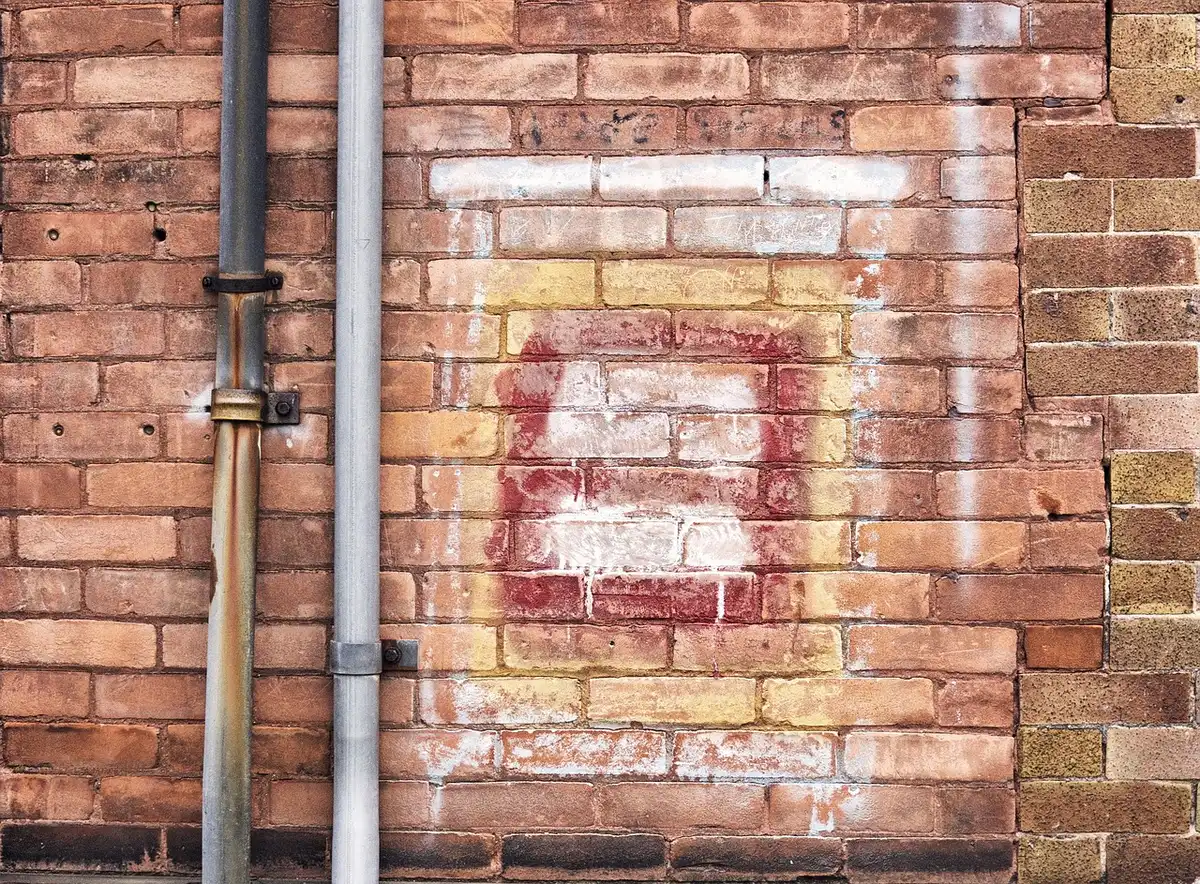Main d'un professionnel appliquant du mastic de scellement autour de tuyauteries et fissures murales
