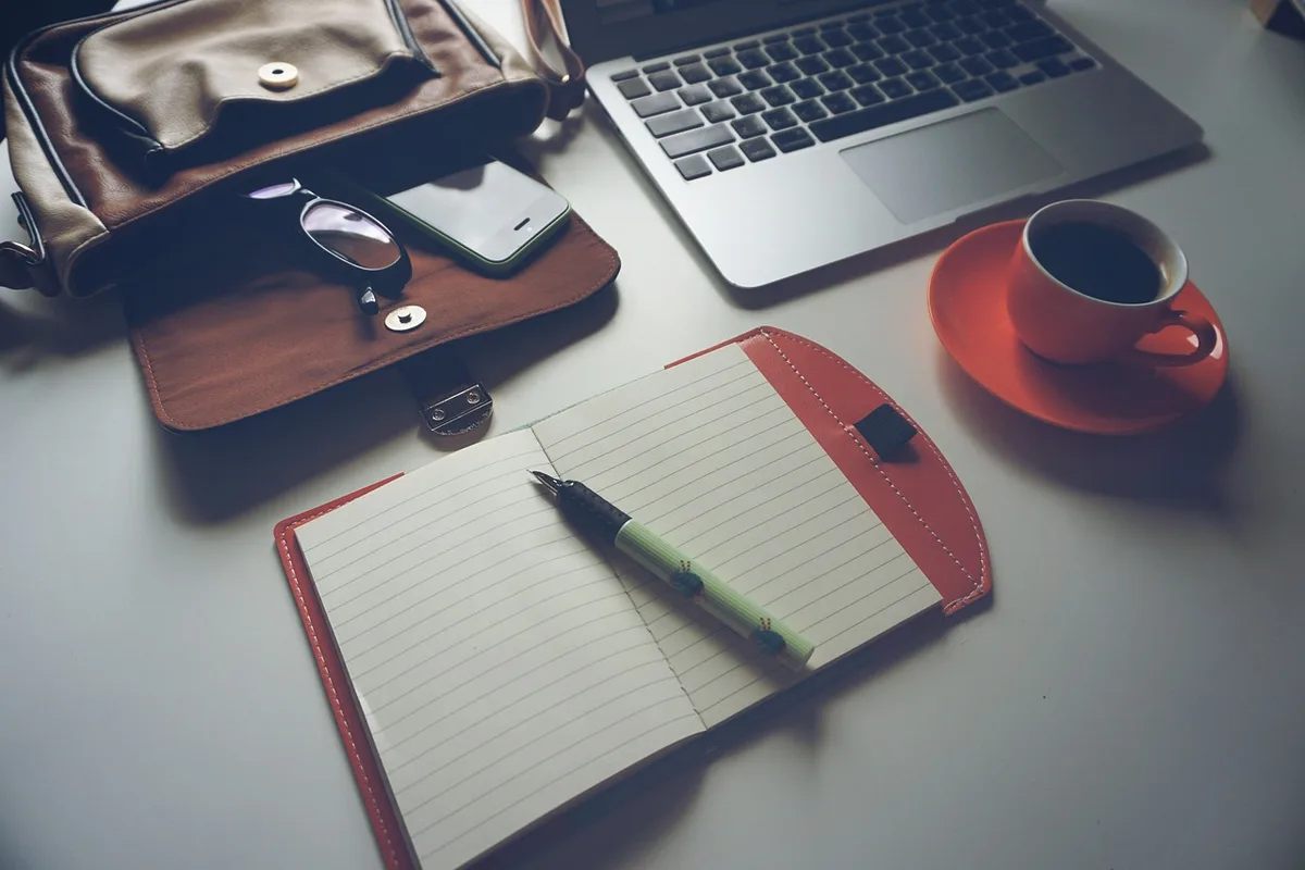 Allée de sellerie avec carnets posés sur un établi et un ordinateur portable, lumière douce
