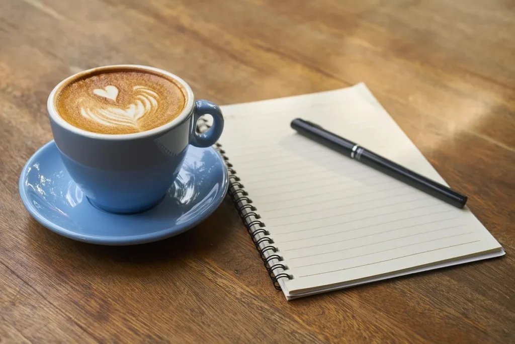 Mains feuilletant un carnet et un agenda sur une table près d'une fenêtre en journée