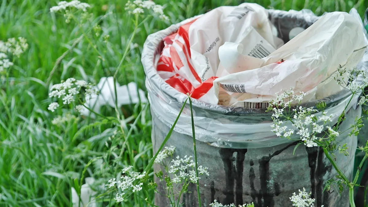 Local poubelles propre avec bacs fermés et sacs rangés en hauteur