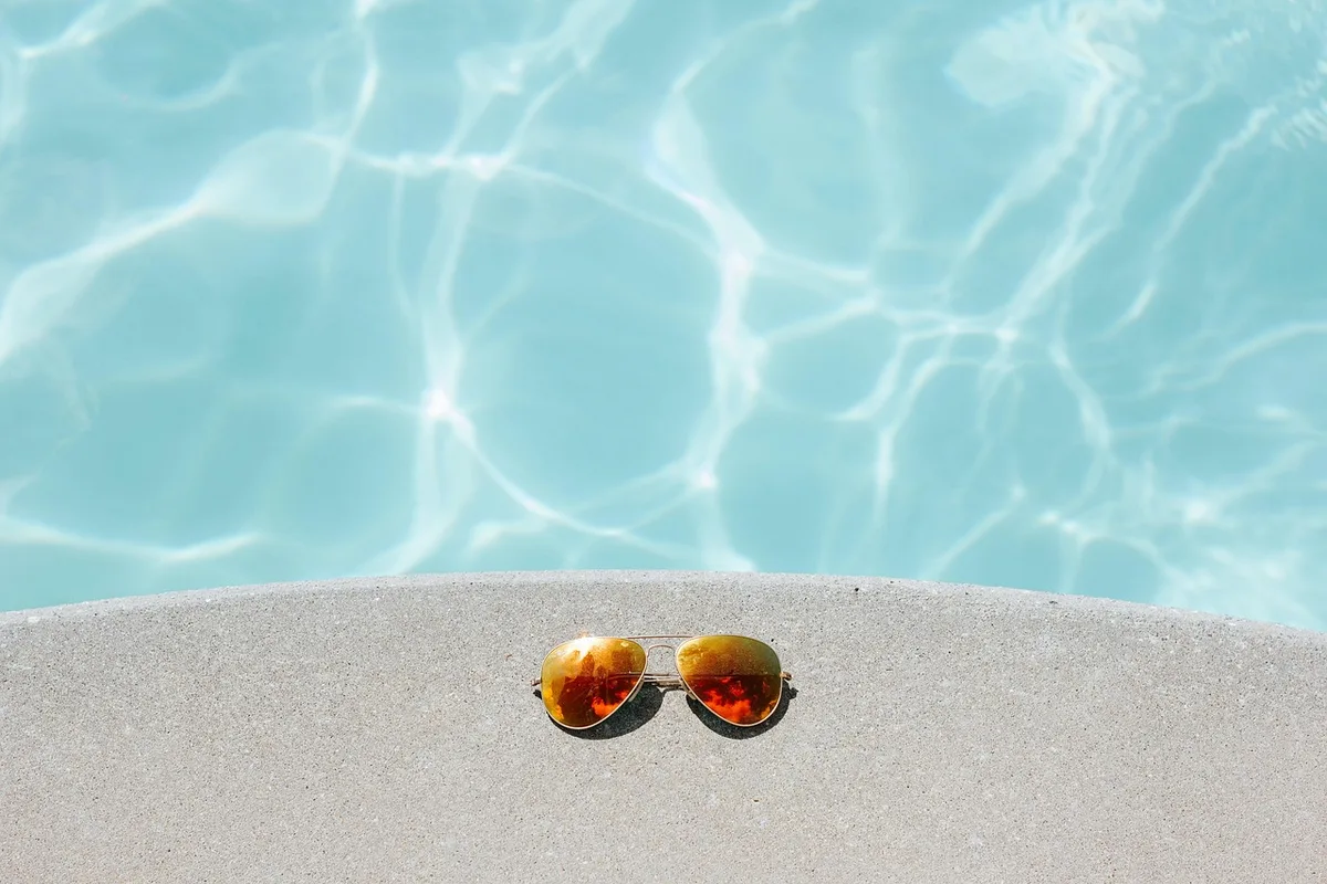 Chien au bord d'une piscine surveillé par une main humaine