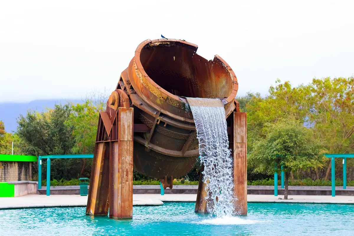 Fontaine et petite cascade dans un bassin en jardin éclairé par le soleil